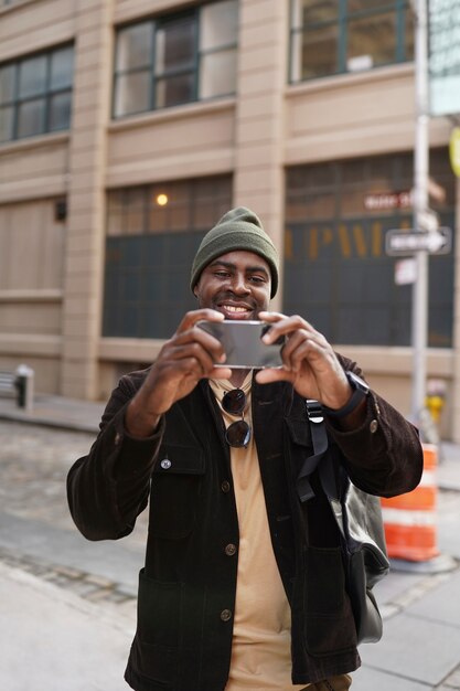 Jeune homme élégant explorant la ville tout en utilisant un smartphone