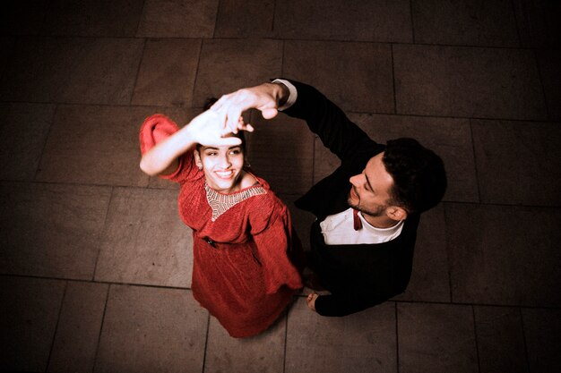 Jeune homme élégant, tenant la main de la danse charmante femme joyeuse