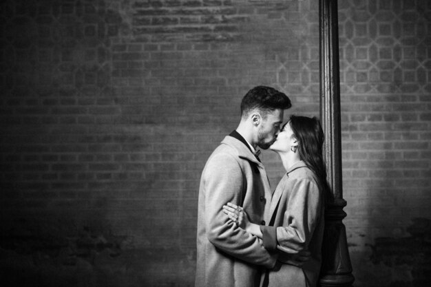Jeune homme embrassant et étreignant femme près de lampadaire