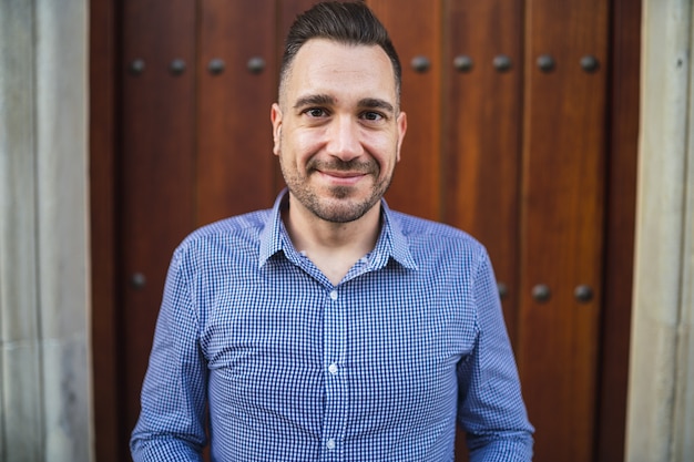 Jeune homme émotionnel avec une chemise bleue debout à la porte avec un léger sourire sur son visage