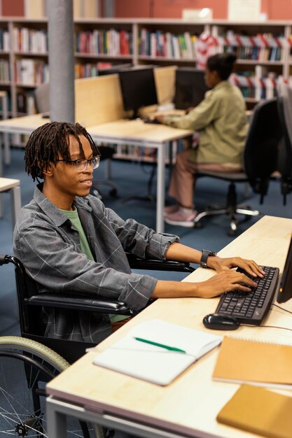 Jeune homme étudiant dans la bibliothèque universitaire