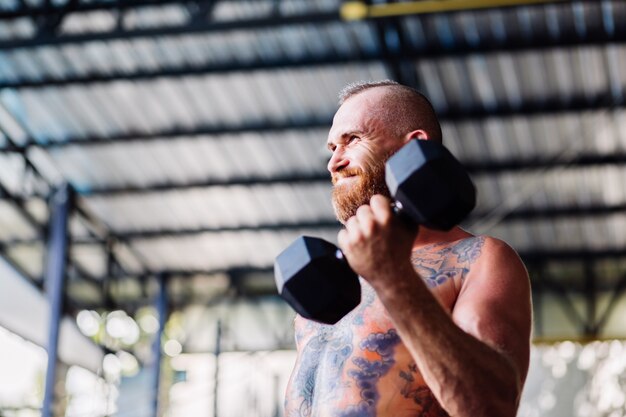 Jeune homme européen barbu musclé tatoué fort muscle faisant un exercice difficile