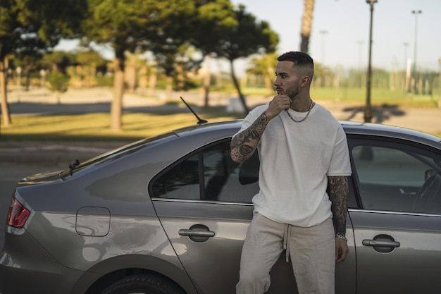 Jeune Homme Européen Tatoué S'appuyant Sur Sa Voiture