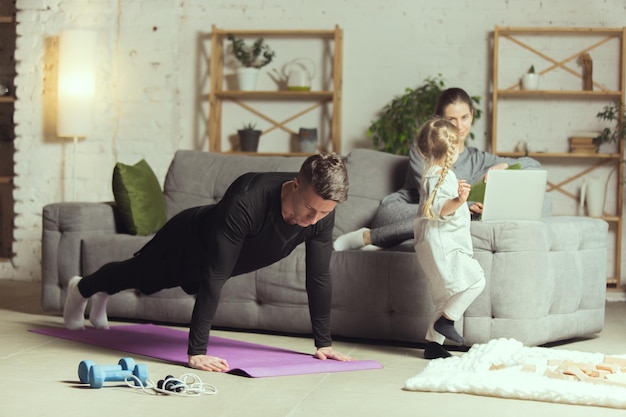 Photo gratuite jeune homme faisant de l'exercice de fitness yoga aérobie à la maison mode de vie sportif s'activer pendant la quarantaine de verrouillage salle de sport à domicile