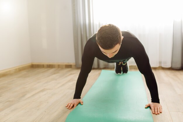 Jeune homme faisant des exercices de sport à la maison