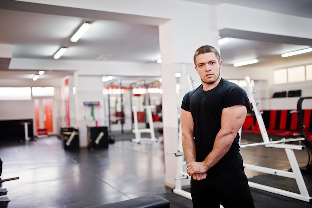 Photo gratuite jeune homme faisant des exercices et travaillant dur dans la salle de gym et appréciant son processus d'entraînement