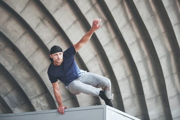 Jeune homme faisant un saut parkour dans l'espace urbain dans la ville ensoleillée printemps été.