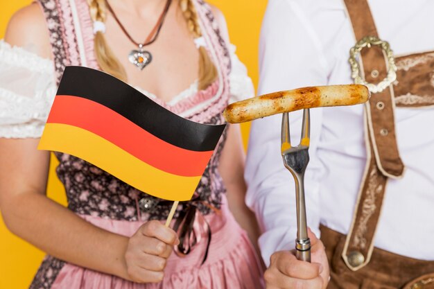 Jeune homme et femme drapeau allemand et saucisses grillées