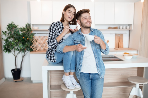 Jeune homme et femme heureux dans la cuisine, petit-déjeuner, couple ensemble le matin, souriant, prenant le thé