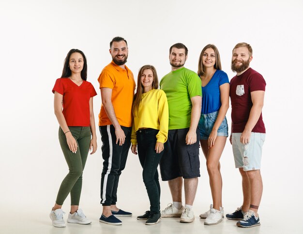 Jeune homme et femme portant les couleurs du drapeau LGBT sur un mur blanc. Modèles caucasiens en chemises lumineuses. Ayez l'air heureux, souriant et étreignant. Fierté LGBT, droits de l'homme et concept de choix.