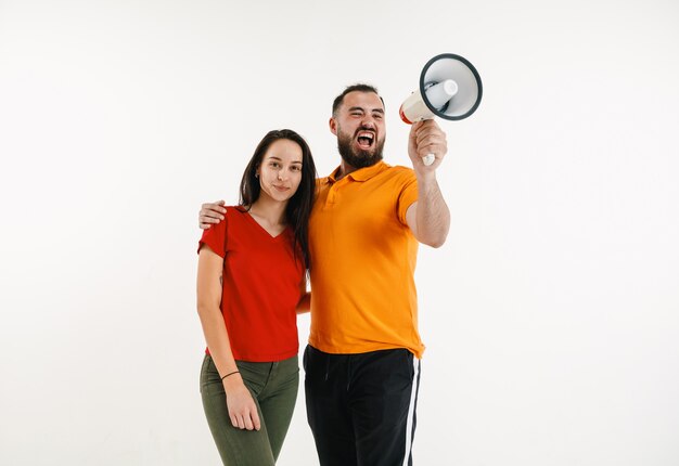 Jeune homme et femme portés dans les couleurs du drapeau LGBT sur fond blanc. Modèles caucasiens en chemises lumineuses.