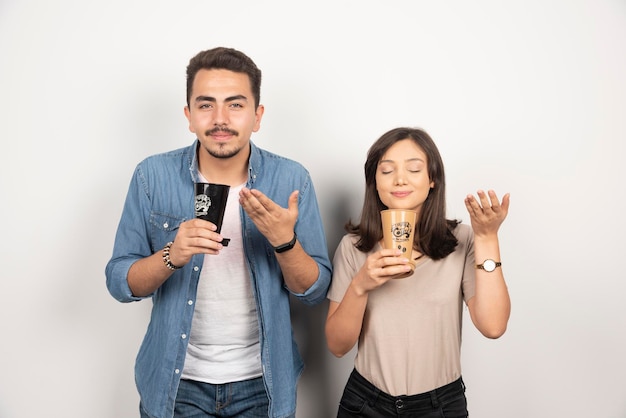 Jeune homme et femme renifle le café aromatique des tasses.