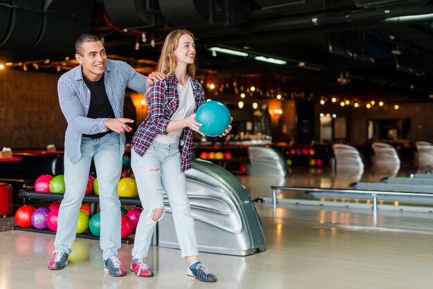 Jeune homme et femme s'amusant dans un club de bowling