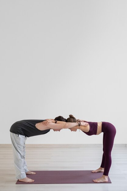 Jeune homme et femme spirituels pratiquant le yoga à l'intérieur