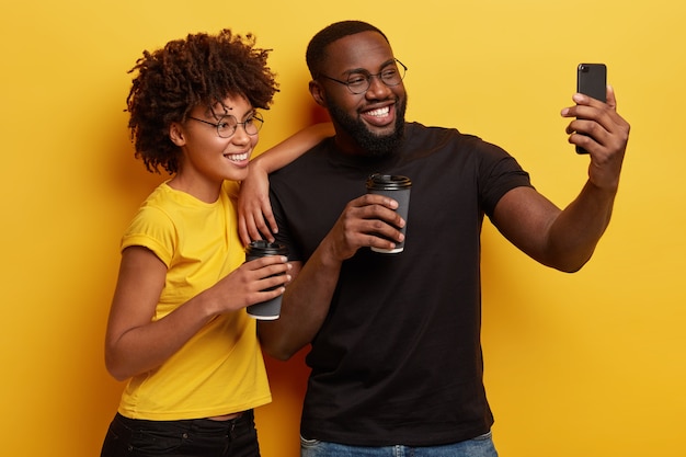 Jeune homme et femme tenant des tasses de café