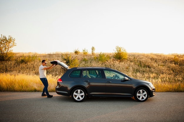 Jeune homme fermant le coffre de la voiture