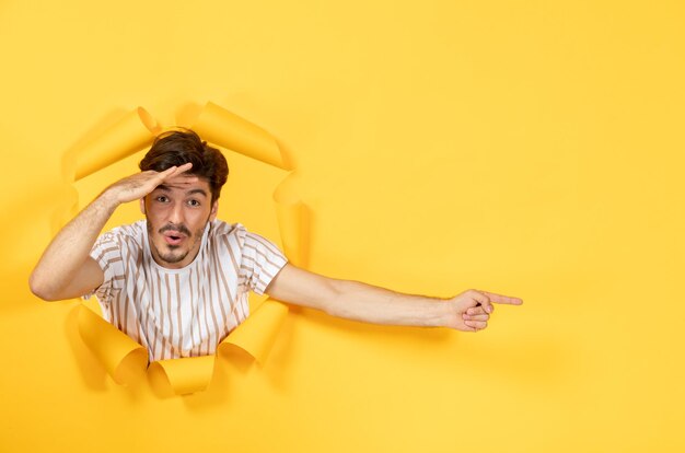 Jeune homme sur fond de papier jaune déchiré type de vente du visage à l'intérieur