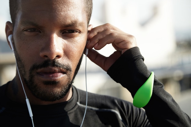 Photo gratuite jeune homme en forme à la plage, écouter de la musique