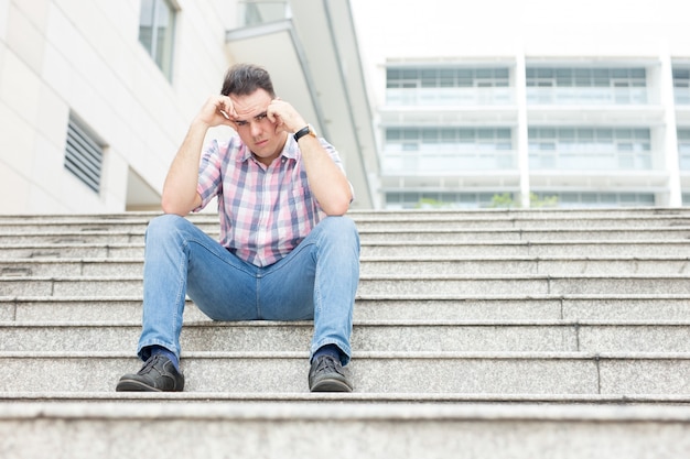 Jeune homme frustré assis sur l&#39;escalier de la ville