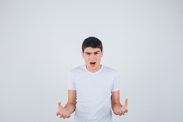 Jeune homme gardant les mains de manière agressive en t-shirt et à l'ennui. vue de face.