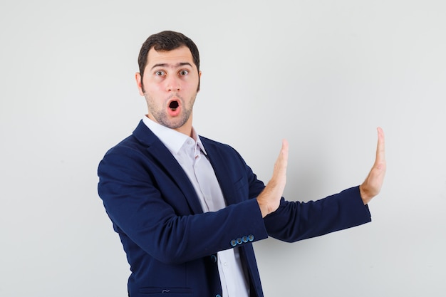 Jeune homme gardant les mains pour se défendre en chemise et veste et à la confiance,