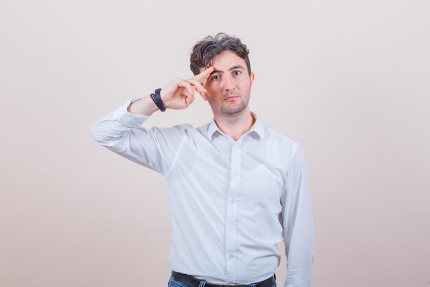 Jeune homme gesticulant avec la main et les doigts en chemise blanche, jeans et à l'air confiant