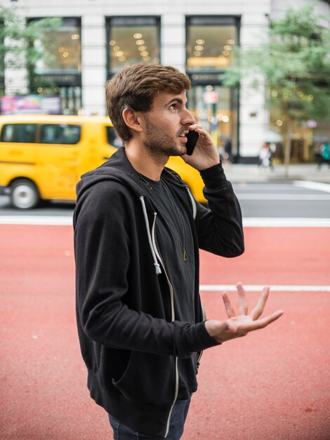 Jeune homme gesticulant en parlant sur smartphone