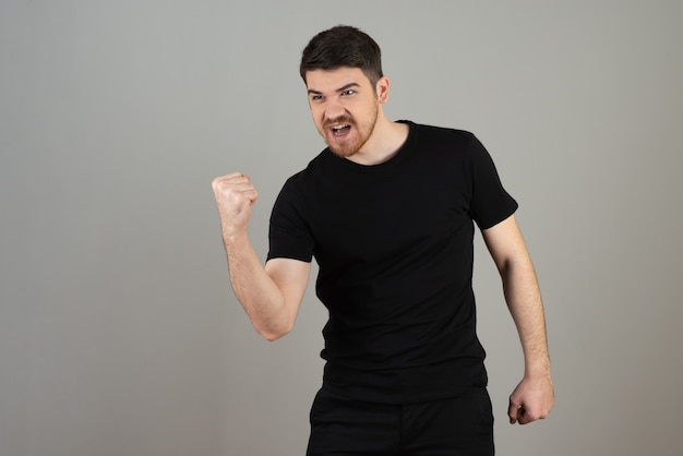 Un jeune homme heureux serre son poing et célèbre quelque chose.