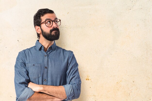 Jeune homme hipster pensant au fond blanc