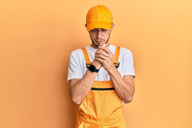 Photo gratuite jeune homme hispanique portant un uniforme de bricoleur souffrant de douleurs aux mains et aux doigts, inflammation de l'arthrite