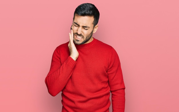 Jeune homme hispanique portant des vêtements décontractés touchant la bouche avec la main avec une expression douloureuse à cause d'un mal de dents ou d'une maladie dentaire sur les dents. dentiste