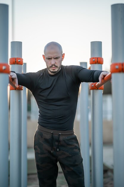 Jeune homme hispanique se reposant après l'exercice sur les barres horizontales