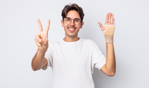 Jeune homme hispanique souriant et sympathique, montrant le numéro deux. concept de bandage à la main