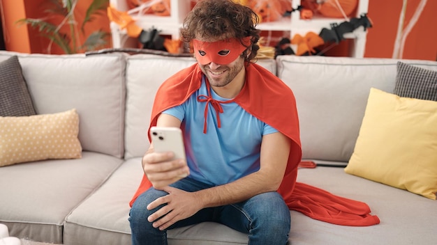 Jeune homme hispanique utilisant un smartphone ayant une fête d'halloween à la maison