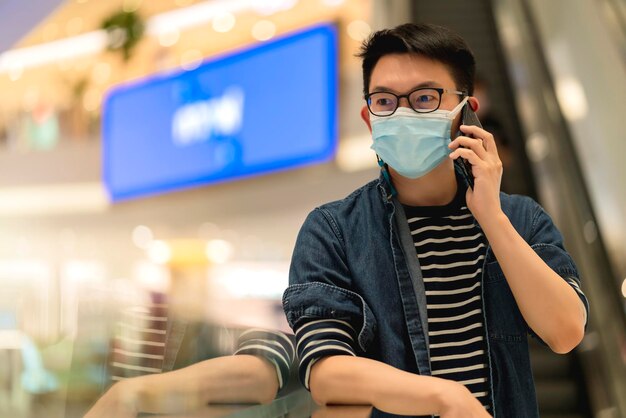 Jeune homme intelligent asiatique attrayant et confiant portant un tissu casul main tenir un smartphone connecter la communication dans le concept d'idées de technologie intelligente de centre commercial