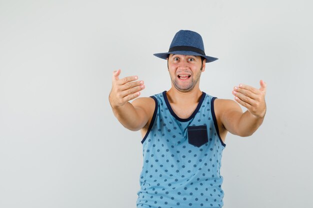 Jeune homme invitant à venir en maillot bleu, chapeau et à l'optimiste.