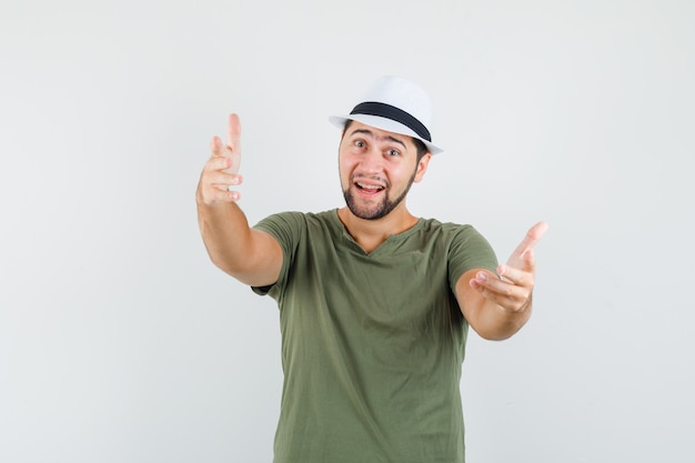 Jeune homme invitant à venir en t-shirt vert et chapeau et à la convivialité