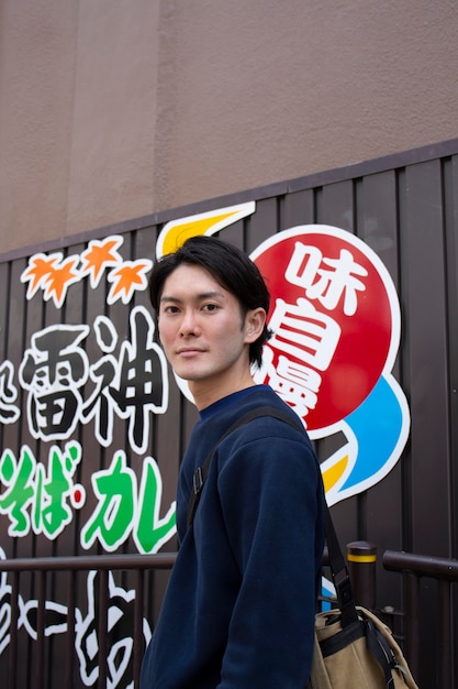 Photo gratuite jeune homme japonais dans un pull bleu dans la ville