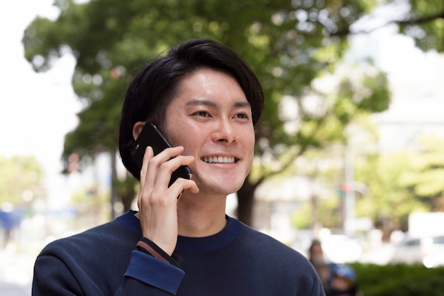 Jeune homme japonais dans un pull bleu à l'extérieur