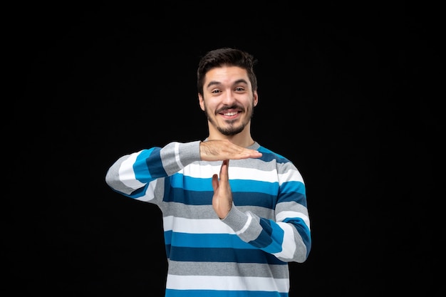 Jeune homme en jersey rayé bleu avec un geste de la main de temps de pause