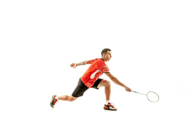 Jeune homme jouant au badminton sur studio blanc. Monter l'athlète masculin isolé sur blanc.