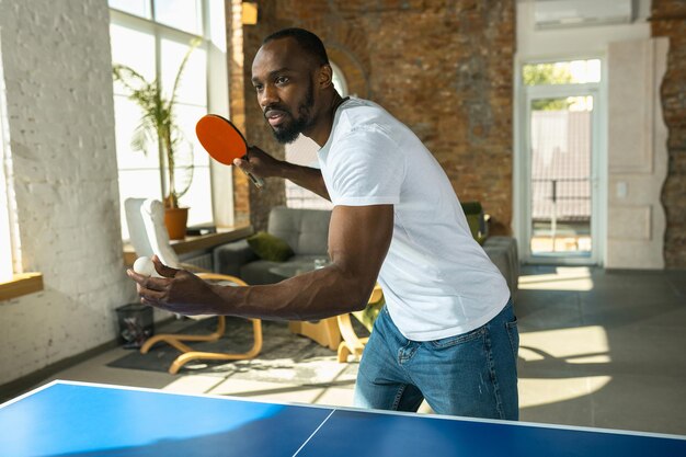 Jeune homme jouant au tennis de table en milieu de travail, s'amusant