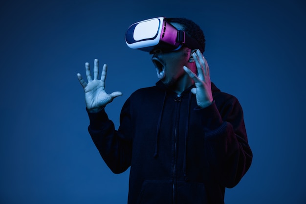 Jeune homme jouant dans des lunettes VR en néon
