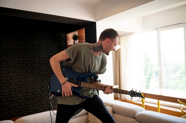 Jeune homme jouant de la guitare à la maison