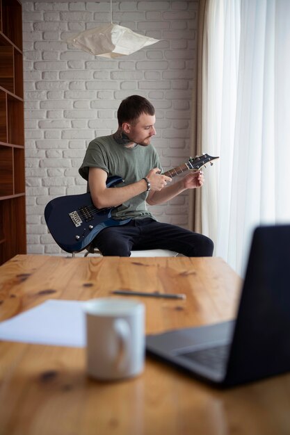 Jeune homme jouant de la guitare à la maison