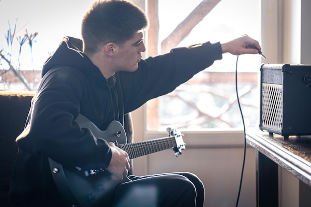 Un jeune homme joue de la guitare électrique dans sa chambre