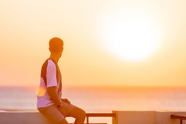 Jeune homme jouissant de la vue sur la mer depuis le balcon