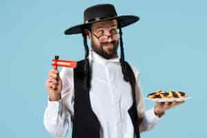 Photo gratuite le jeune homme juif orthodoxe avec des biscuits hamantaschen pour le festival pourim
