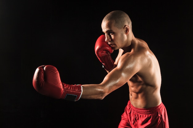 Le jeune homme kickboxing sur fond noir