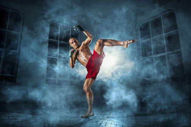 Photo gratuite le jeune homme kickboxing en fumée bleue